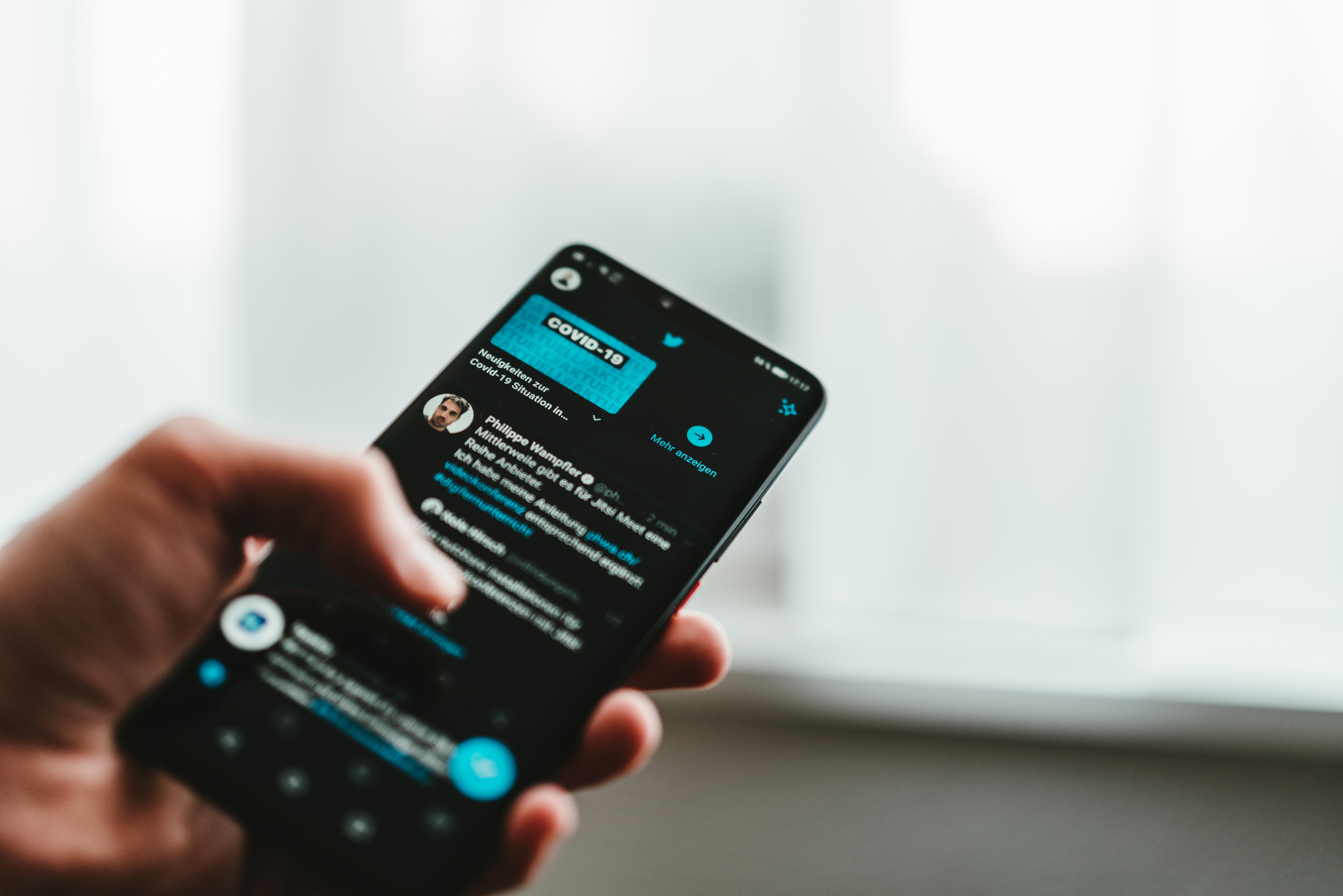 man holding phone and looking at tweets for sentiment analysis twitter