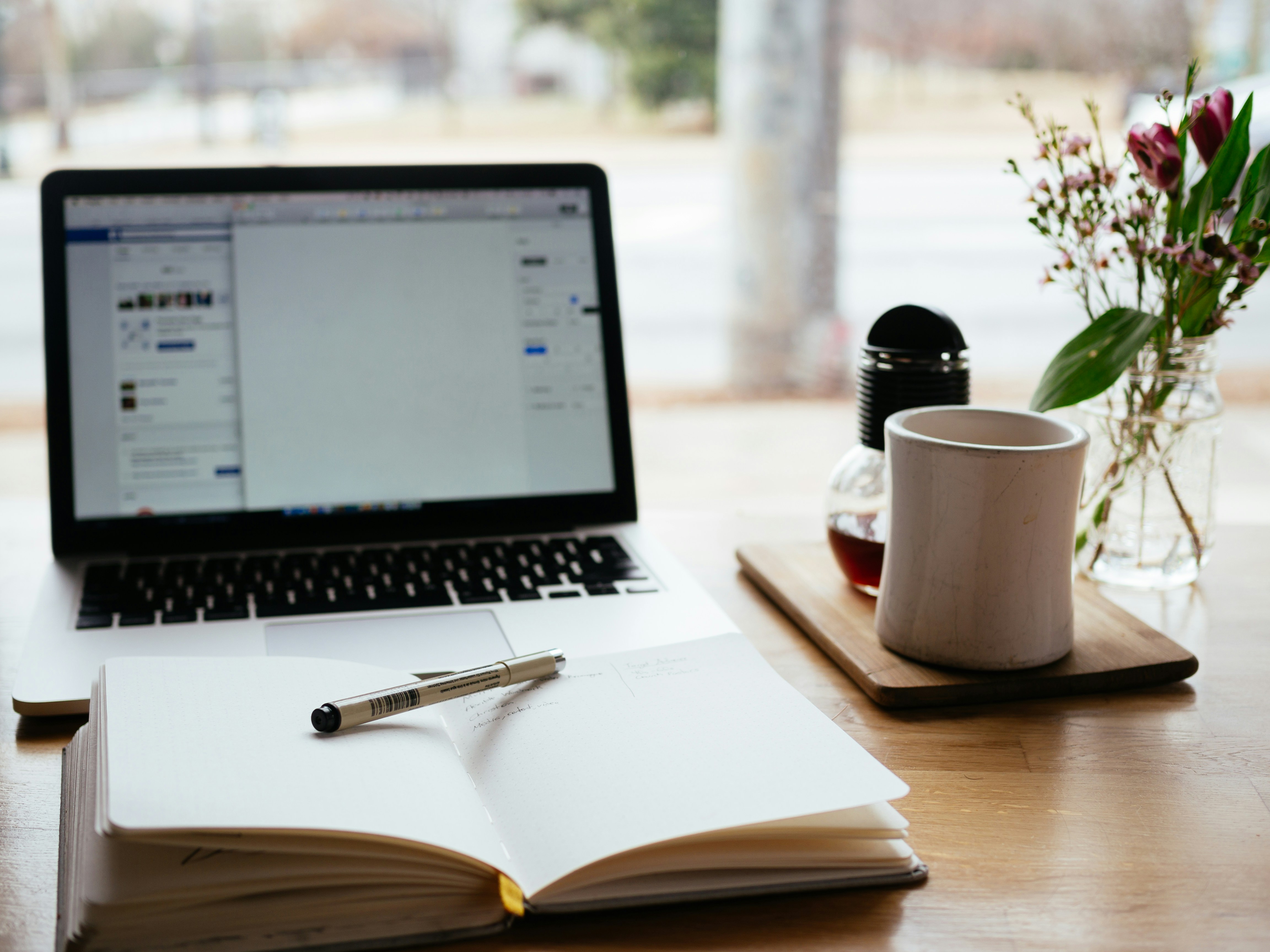notebook and laptop on table - How To Rephrase A Thesis Statement